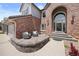 Inviting front patio with brickwork and seating area, leading to an arched doorway entrance on a sunny day at 10 Sand Cherry, Littleton, CO 80127
