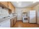 Quaint kitchen with white appliances, light wood cabinetry, and vintage style flooring at 5240 Dudley St, Arvada, CO 80002