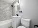 Bathroom with a modern sink and a tub-shower combo featuring beautiful marble-style tile at 832 Dahlia St, Denver, CO 80220