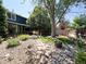 Landscaped backyard featuring a stone path, mature trees, and patio seating area at 4049 S Quatar St, Aurora, CO 80018