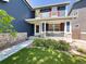 Inviting two-story home with blue siding, red shutters, a stone foundation, covered porch, and lush green lawn at 4049 S Quatar St, Aurora, CO 80018