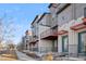 Modern townhomes featuring private balconies, red metal accents, and a combination of stucco and stone exteriors at 7928 E 54Th Pl, Denver, CO 80238