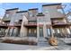 Modern townhome showcases stucco and stone exterior with private patio and sleek, black metal railings at 7928 E 54Th Pl, Denver, CO 80238
