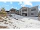 Two-story home with deck, snowy yard, and hillside view at 616 Scrubjay Cir, Castle Rock, CO 80104