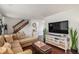 Bright living room with a large TV, plush seating, and staircase access at 8691 Bluebunch Ct, Parker, CO 80134