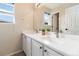 Bright bathroom with double sinks, a large mirror, white cabinets and countertops, and a view from a window at 9169 Fox Fire Way, Highlands Ranch, CO 80129