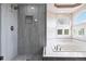 Modern bathroom featuring a glass-enclosed shower with gray tile and soaking tub with bright window at 9169 Fox Fire Way, Highlands Ranch, CO 80129
