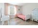 A cozy bedroom featuring light wood floors, soft pink accents, a decorative armoire, and a bright window at 9169 Fox Fire Way, Highlands Ranch, CO 80129