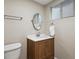 Bathroom with a wood vanity, a round mirror and a toilet at 12752 W Asbury Pl, Lakewood, CO 80228