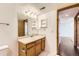 Bathroom with wood cabinets, a large mirror, light colored countertops, and a doorway leading to another room at 1351 S Cathay Ct # 102, Aurora, CO 80017