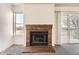 Close up of the brick fireplace and mantle in the light filled living room with a sliding glass door and a large window at 1351 S Cathay Ct # 102, Aurora, CO 80017