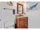 Charming powder room boasting granite countertop vanity, decorative mirror, and boat themed artwork at 9805 Garrison Ct, Broomfield, CO 80021