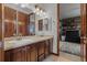 Bathroom featuring a double vanity and wood cabinets, with a view into bedroom at 25312 E Glasgow Pl, Aurora, CO 80016