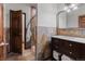 Bathroom featuring a marble vanity, mirror, and tiled shower behind a wood door at 25312 E Glasgow Pl, Aurora, CO 80016