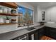 Modern kitchen sink area with floating shelves and a view of the backyard at 25312 E Glasgow Pl, Aurora, CO 80016