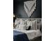 Detailed view of a Primary bedroom's bed with plush pillows and a decorative macrame wall hanging at 25312 E Glasgow Pl, Aurora, CO 80016