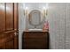 Stylish powder room with chevron wallpaper, modern vanity, vessel sink, and round gold mirror at 25312 E Glasgow Pl, Aurora, CO 80016