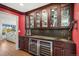 Elegant wet bar featuring custom cabinetry, a built-in wine fridge, and display shelving with glassware at 4682 S Franklin St, Englewood, CO 80113