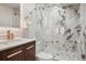 A modern bathroom featuring marble walls, a glass-enclosed shower, and vanity with wooden cabinetry at 645 S Park Ave # 302, Breckenridge, CO 80424
