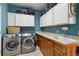 Functional laundry room with modern washer/dryer and plenty of storage cabinets at 6296 W Prentice Ave, Littleton, CO 80123