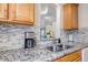 Updated kitchen features granite countertops, stainless steel sink, and gray mosaic backsplash at 9797 E Peakview Ave # C1, Englewood, CO 80111