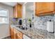 Well-lit kitchen with granite countertops, stainless steel sink, and white and gray mosaic backsplash at 9797 E Peakview Ave # C1, Englewood, CO 80111