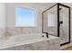 Modern bathroom with a luxurious soaking tub, large window, and separate glass-enclosed shower with black hardware at 42964 Colonial Trl, Elizabeth, CO 80107