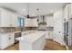Well-lit kitchen with white cabinetry, stainless steel appliances, a kitchen island, and hardwood floors at 42964 Colonial Trl, Elizabeth, CO 80107