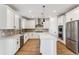 Bright kitchen featuring white cabinetry, stainless steel appliances, a herringbone backsplash, and a center island at 42964 Colonial Trl, Elizabeth, CO 80107