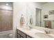 Bright bathroom with double sinks, tiled shower, and framed botanical prints at 16568 W 92Nd Pl, Arvada, CO 80007