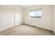 Minimalist bedroom featuring neutral carpet, a large window, and a closet with sliding doors at 16568 W 92Nd Pl, Arvada, CO 80007