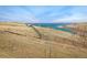 Scenic lake view with rolling hills and a walking path, ideal for enjoying outdoor recreation at 16568 W 92Nd Pl, Arvada, CO 80007