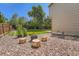 Backyard with fire pit, seating made of tree trunks, gravel, green grass and trees at 5534 S Wenatchee St, Aurora, CO 80015