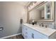 Bathroom with a white double sink vanity with marble countertop, framed mirror, and wood flooring at 5534 S Wenatchee St, Aurora, CO 80015