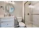 Beautiful bathroom with a glass door shower, white vanity, and decorative round mirror at 5534 S Wenatchee St, Aurora, CO 80015