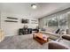 Cozy living room featuring a comfortable sofa, a work area, carpet flooring, and large window at 5534 S Wenatchee St, Aurora, CO 80015