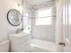 Well-lit bathroom featuring a vanity with a round mirror and a shower with tiled walls and modern fixtures at 1476 W Dakota Ave, Denver, CO 80223