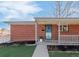 Inviting brick home featuring a cozy covered front porch with a blue door and fresh landscaping at 1476 W Dakota Ave, Denver, CO 80223