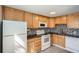 Kitchen with wooden cabinets, black countertops, and white appliances at 1182 N Clermont St # 101, Denver, CO 80220