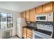 Kitchen with tiled floor, light wood cabinets, white appliances and black and white backsplash at 1182 N Clermont St # 101, Denver, CO 80220