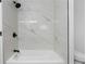 Modern bathroom features white marble-look tile, dark fixtures, and soaking tub at 12635 E Pacific Cir # A, Aurora, CO 80014