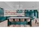 A modern kitchen features a large island with seating, stainless steel appliances, and sleek, emerald green cabinetry at 111 S Hudson St, Denver, CO 80246