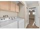 Functional laundry area featuring cabinets and machines, with access to a bedroom at 1272 S Crystal Way, Aurora, CO 80012