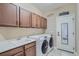 Well-organized laundry room with upper cabinets, utility sink, and modern front load machines at 23993 E Briarwood Dr, Aurora, CO 80016