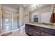 Well-lit bathroom featuring a double vanity with granite countertop and glass enclosed shower at 12604 Madison Way, Thornton, CO 80241