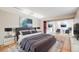 Well-lit bedroom with a comfortable bed, accent chairs, and mounted televisions at 7382 E Bates Dr, Denver, CO 80231