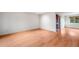 Bright, empty room with beautiful wood floors and great light from a large window at 7382 E Bates Dr, Denver, CO 80231