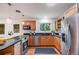 Eat-in kitchen boasts wooden cabinets, stainless steel appliances, and a window with a wooded view at 7382 E Bates Dr, Denver, CO 80231
