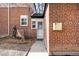 Brick exterior featuring a white security door, adjacent to a unique tree stump statue at 1168 Kearney St, Denver, CO 80220