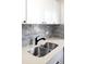 Modern kitchen sink with stainless steel basin, sleek black faucet, and stylish gray backsplash at 1168 Kearney St, Denver, CO 80220